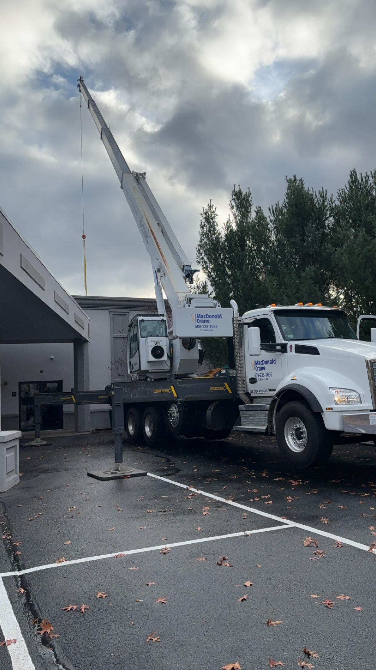 50-ton crane from MacDonald Crane positioned in a parking lot, demonstrating maneuverability and compactness for urban job sites, with a boom extended for lifting operations.
