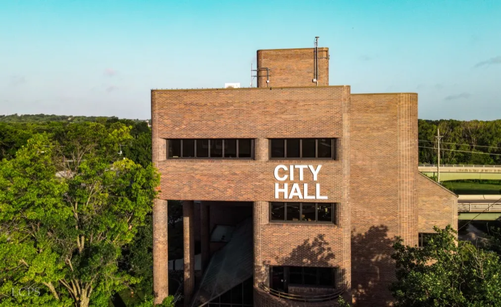 City Hall building in Lawrence, Massachusetts, featuring prominent signage and surrounded by greenery, representing key landmarks in the area.