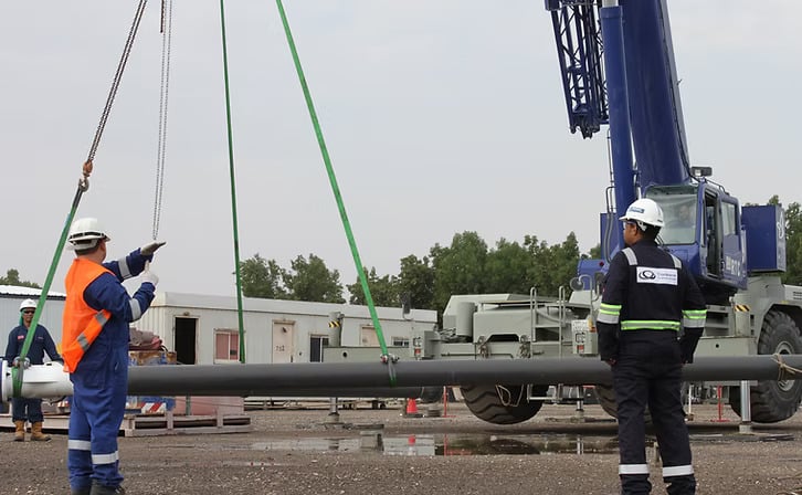 Crane operators coordinating heavy lifting with a boom crane, showcasing safe rigging practices in a construction environment.