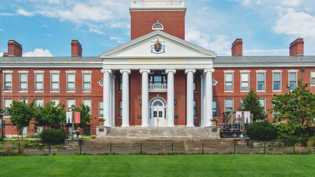 Bridgewater State University building with classical architecture, featuring columns and a prominent entrance, surrounded by greenery, relevant to crane rental services in Bridgewater, MA.