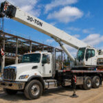 30-ton boom truck on construction site, showcasing crane capabilities for efficient lifting and rigging services in Boston, MA.
